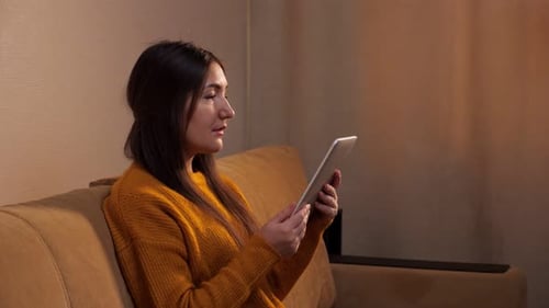 Woman Relaxing on Couch Using Tablet
