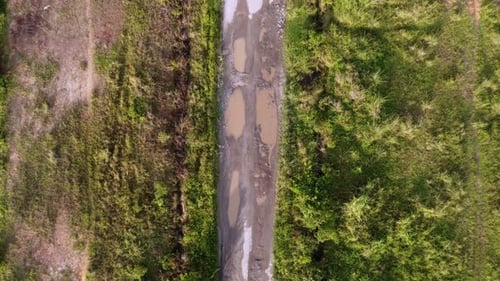 Aerial top down descending broken rural road
