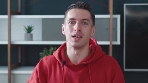 Engaging Man Communicates Directly to Camera Wearing Red Hoodie