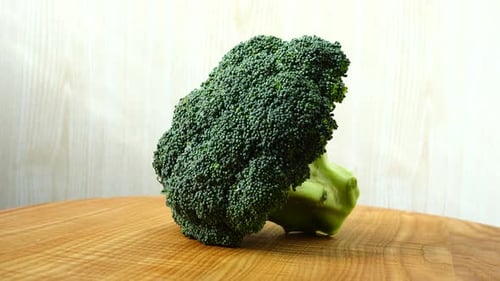 Fresh Green Broccoli Floret Rotating on Wooden Surface