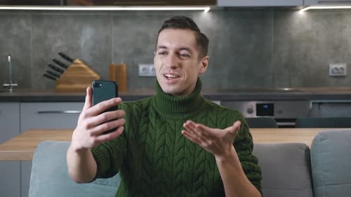 Smiling Man Video Calling on Smartphone at Home