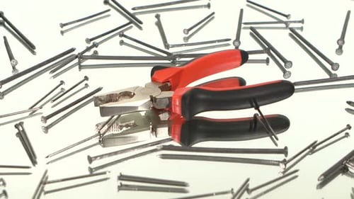Metal Pliers and Nails Rotating on White Surface