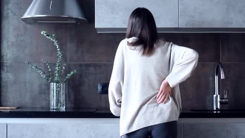 Woman with Backache in kitchen