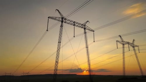 Dark Silhouette of High Voltage Towers with Electric Power Lines at Sunrise