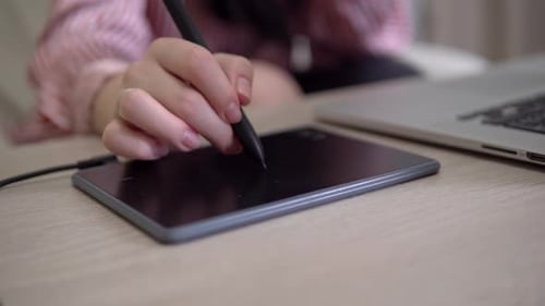 Hand Using Stylus on Graphics Tablet with Laptop