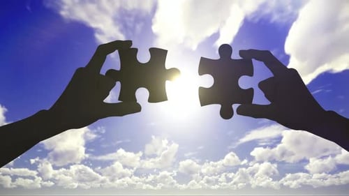 Silhouetted Hands Connect Puzzle Pieces Against Blue Sky