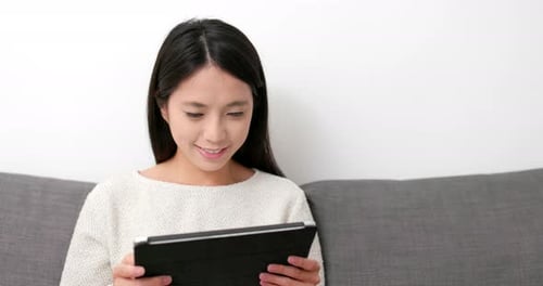 Woman Uses Tablet Device Sitting on Couch at Home