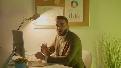 Jovem funcionário trabalhando na mesa e dançando com colegas curtindo a festa no escritório à noite