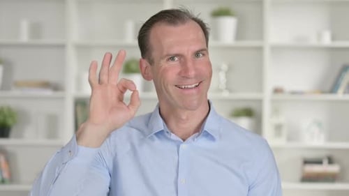 Porträt eines positiven Geschäftsmannes mittleren Alters mit OK-Zeichen