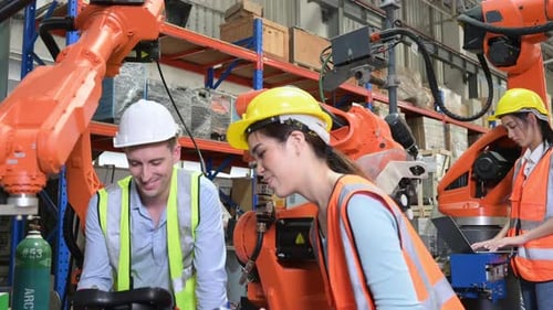 Männliche und weibliche Ingenieure inspizieren den kürzlich installierten Schweißroboter