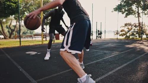 Caucasian Basketball Player Dribbles the Ball Against an African American and Makes an Effective