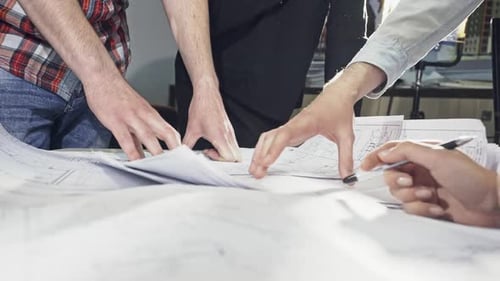 Team Inspecting Blueprints in Bright Office