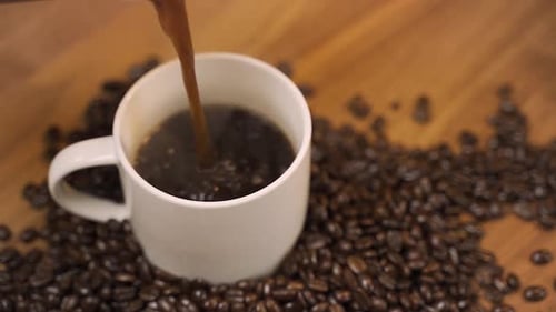 Pouring Steaming Coffee into Mug on Wooden Surface