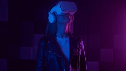 Young Woman in Futuristic VR Headset Interacting with Cyberspace Under Neon Light in Dark Studio