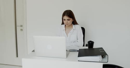 Young Happy Girl Smiling at Laptop During Online Chat at Workplace in Office