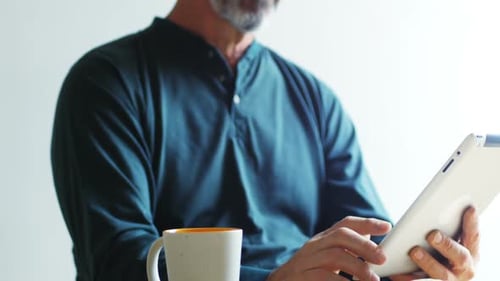Man using digital tablet while having cup of coffee 4k