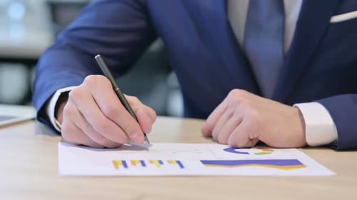 Nahaufnahme der Hände eines Geschäftsmannes, der Berichte auf Papier studiert