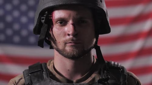 Soldier in Helmet with Blood Removes Helmet