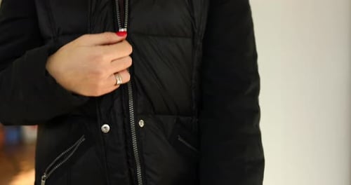 Woman's hand unfasten the zipper on a black jacket