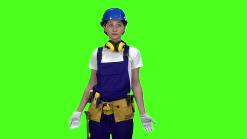 Builder Girl in a Helmet and Suit Looks Around . Green Screen. Slow Motion
