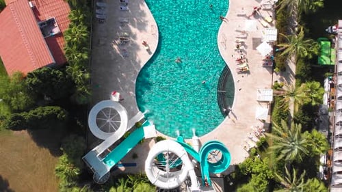 Fly Over a Large Pool with Blue Water and a Lot of Tourists in Hot Weather