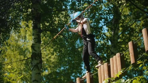 Woman Crossing a Construction of the Rope and Stumps - an Entertainment Attraction in the Green Park