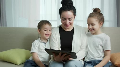 Mother and Children Enjoying Tablet Device Together Indoors