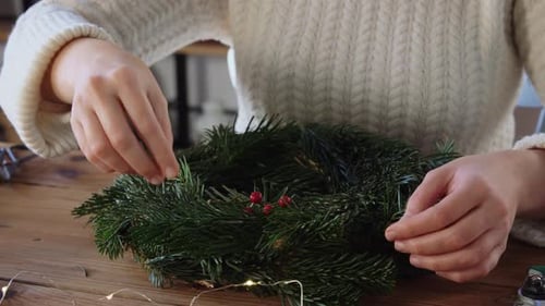 Woman Decorating Christmas Wreath with Berries