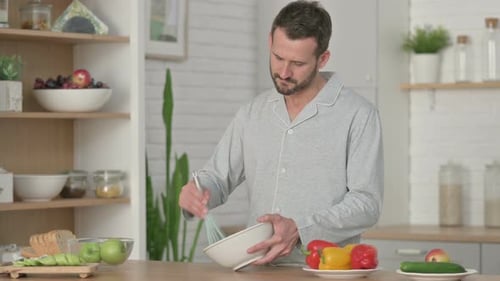 Man Prepares Food in Kitchen with Whisk