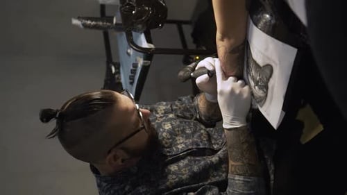 Tattoo Artist Inks Client Arm with Dark Design