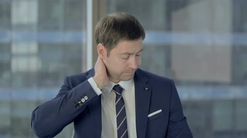 Adult Man Massaging Stiff Neck in Office Setting