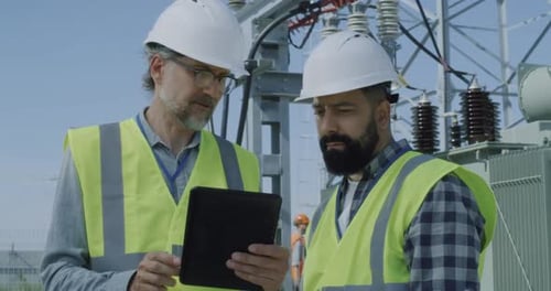 Men in Hard Hats Discuss Work at Transformer Station