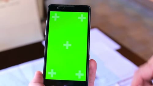 Construction engineer using a smartphone with a green screen looking for information on the internet