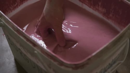 Vue rapprochée d'une potière trempant un pot dans de la peinture dans un atelier de poterie