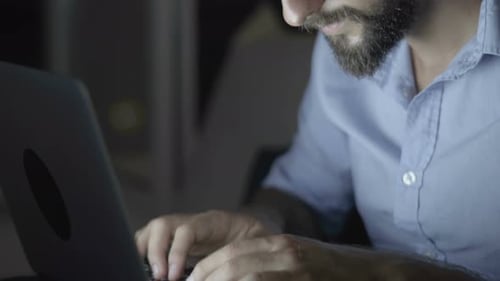Man With Beard Typing on Laptop at Night