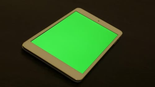 Silver PC tablet with green screen display on wooden table 4K 2160p UltraHD footage - Silver tablet