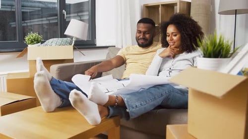 Couple Looking at Blueprints in a House Filled Boxes