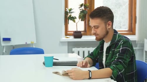 Young Adult Reading Book and Drinking Coffee