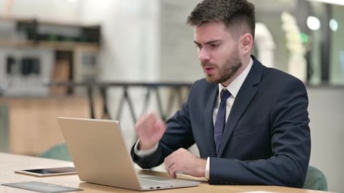 Sick Young Businessman with Laptop Coughing in Office