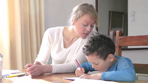 Junge macht Hausaufgaben und lernt zu Hause mit Mutter mit Kind, die an einem Tisch sitzt Stockvideos