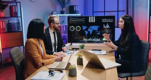 Businesspeople Sitting at Meeting Table in Evening Office and Making Unity and Trust Symbol