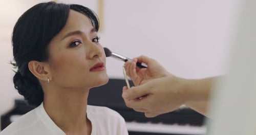 Asiatische Hochzeits-Maskenbildnerin schminkt sich für die Braut. Künstler, der Kosmetik auf das Gesicht der Braut aufträgt.
