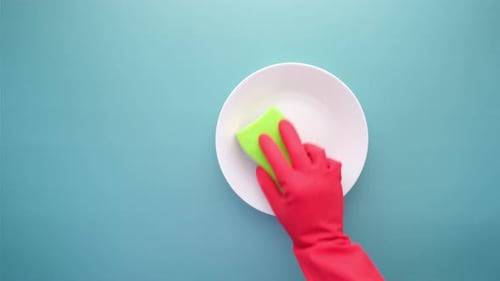 Arm in Red Glove Cleans White Plate with Sponge