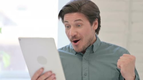Man Celebrates Good News on Tablet