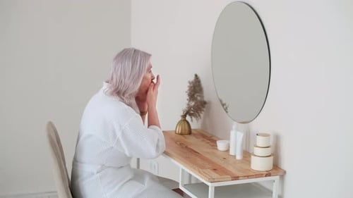 Woman Applies Lotion to Face in Morning