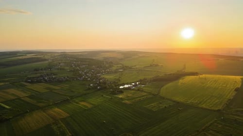Aerial Landscape View of Green Cultivated Agricultural Fields with Growing Crops and Distant Village