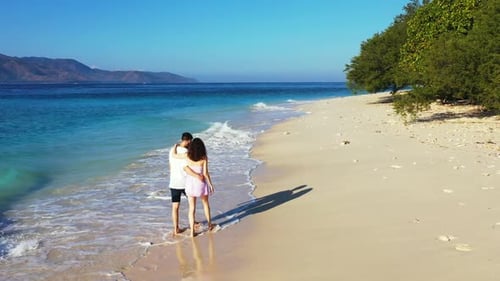 Young couple engaged on exotic sea view beach voyage by blue green sea and white sandy background of