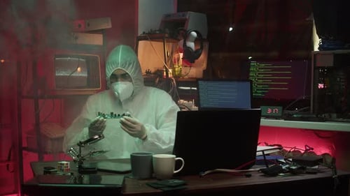 Individual in Protective Suit Examining Circuit Board