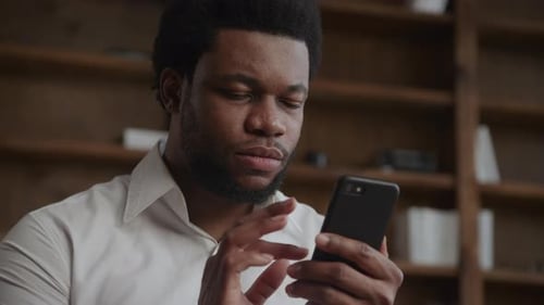 Portrait of a Young Adult Businessman Recieving Good News on His Smart Phone in His Office