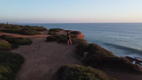 Young Adult Stretching on a Cliff at Sunset